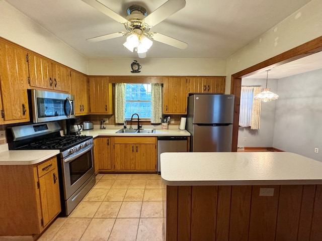 kitchen featuring pendant lighting, ceiling fan with notable chandelier, sink, light tile patterned floors, and appliances with stainless steel finishes