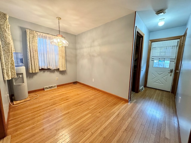 unfurnished dining area with hardwood / wood-style floors and a notable chandelier