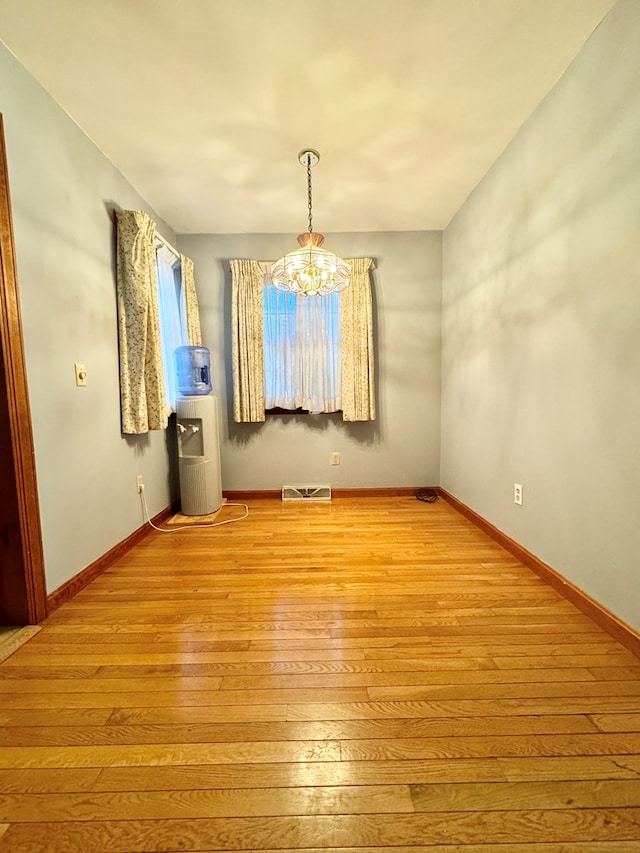 empty room featuring light hardwood / wood-style floors and an inviting chandelier