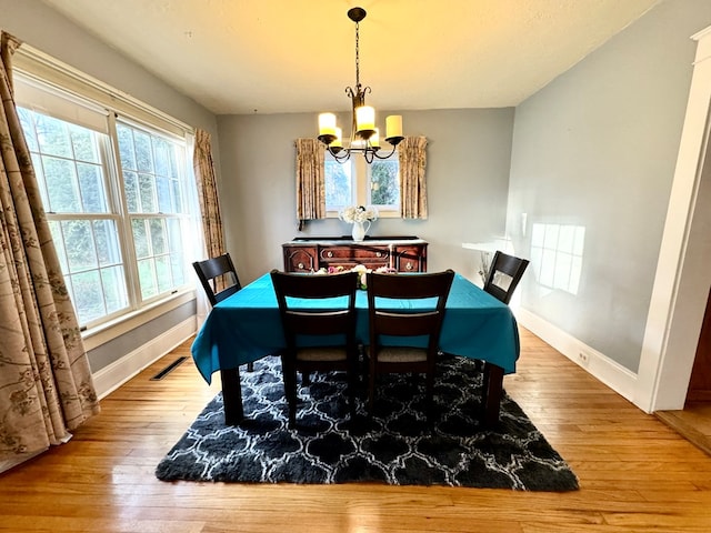 dining space featuring wood-type flooring and a notable chandelier