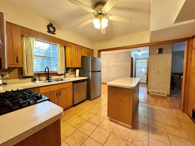 kitchen featuring ceiling fan, sink, a center island, decorative backsplash, and appliances with stainless steel finishes