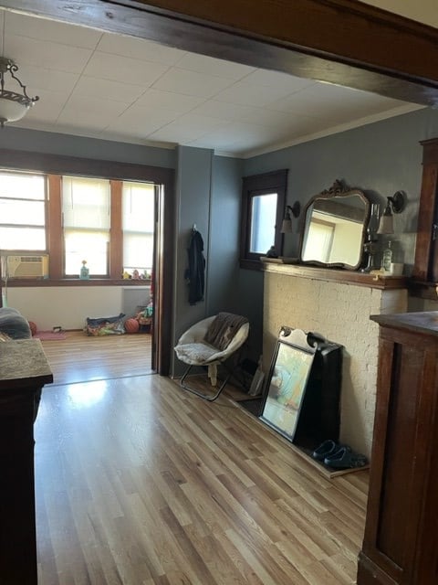 interior space with cooling unit, wood-type flooring, and ornamental molding