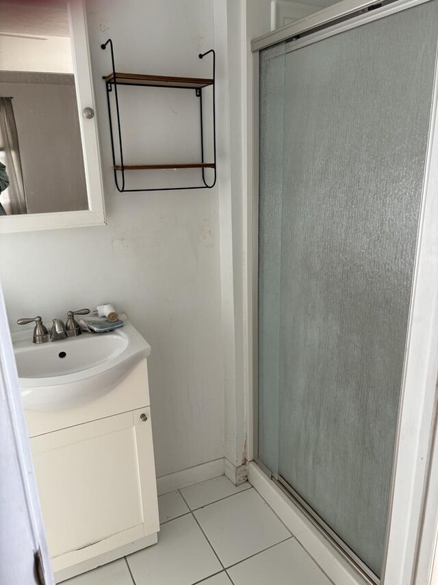 bathroom featuring tile patterned flooring, vanity, and a shower with shower door