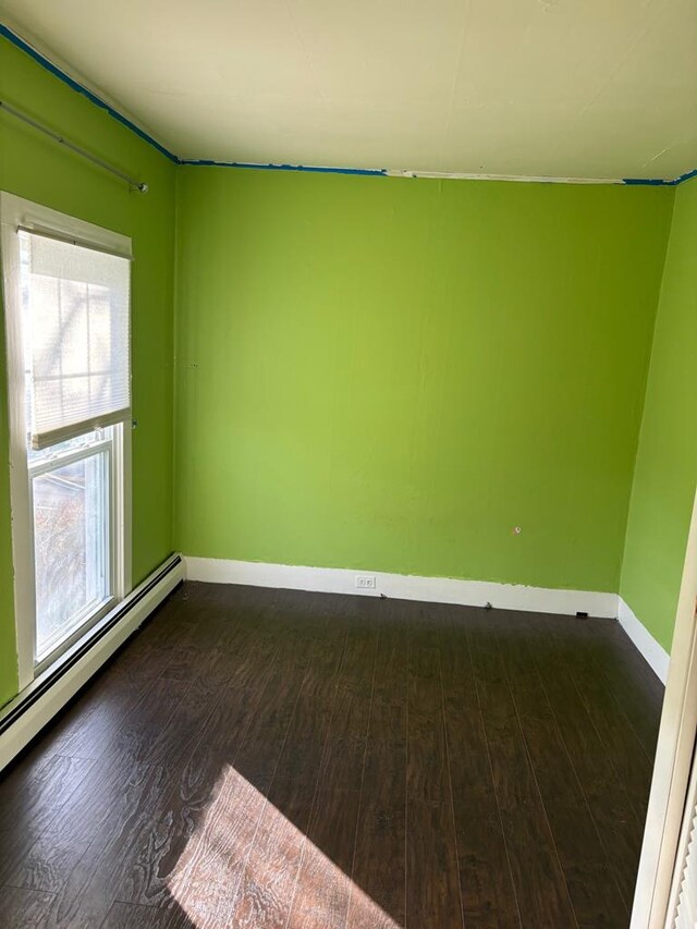 spare room with dark hardwood / wood-style floors and a baseboard radiator