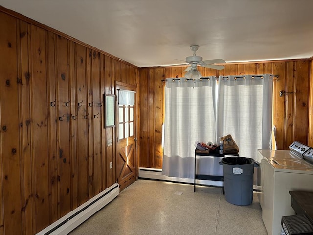 dining room featuring a baseboard heating unit, wooden walls, washer and dryer, and ceiling fan