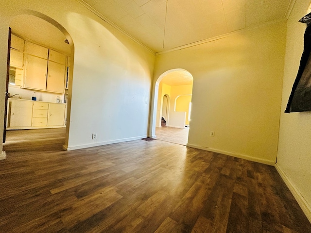 empty room with ornamental molding, dark hardwood / wood-style floors, and a high ceiling