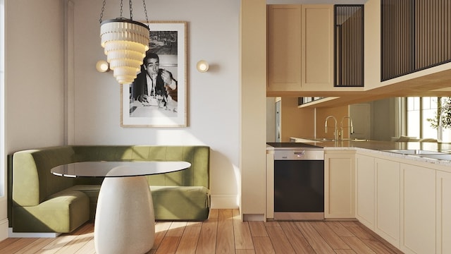 interior space with dishwashing machine, sink, hanging light fixtures, and light hardwood / wood-style flooring