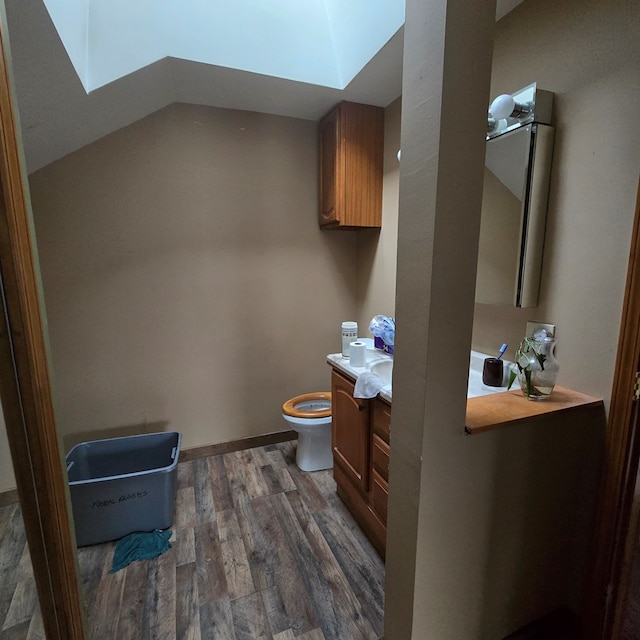 bathroom featuring a skylight, hardwood / wood-style floors, vanity, and toilet