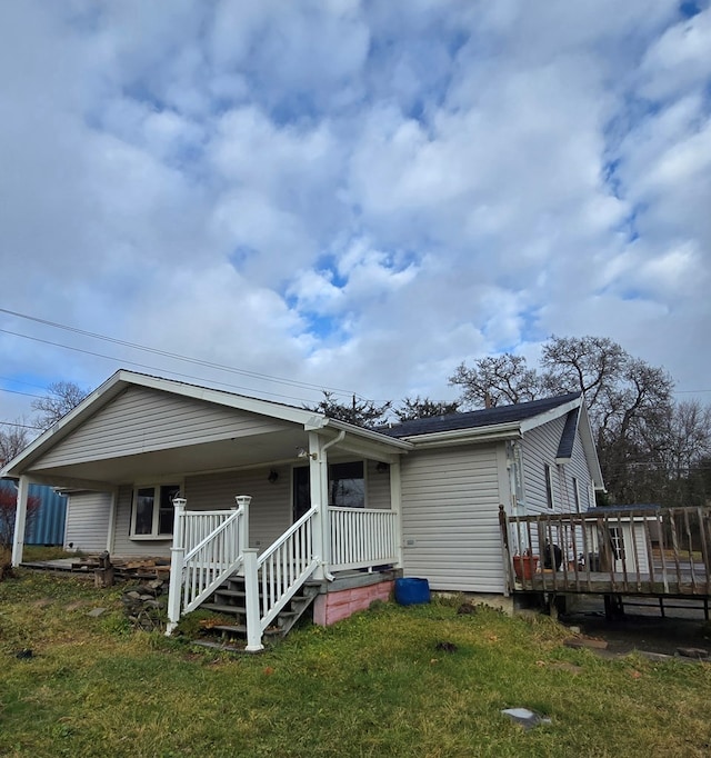 back of house featuring covered porch and a yard