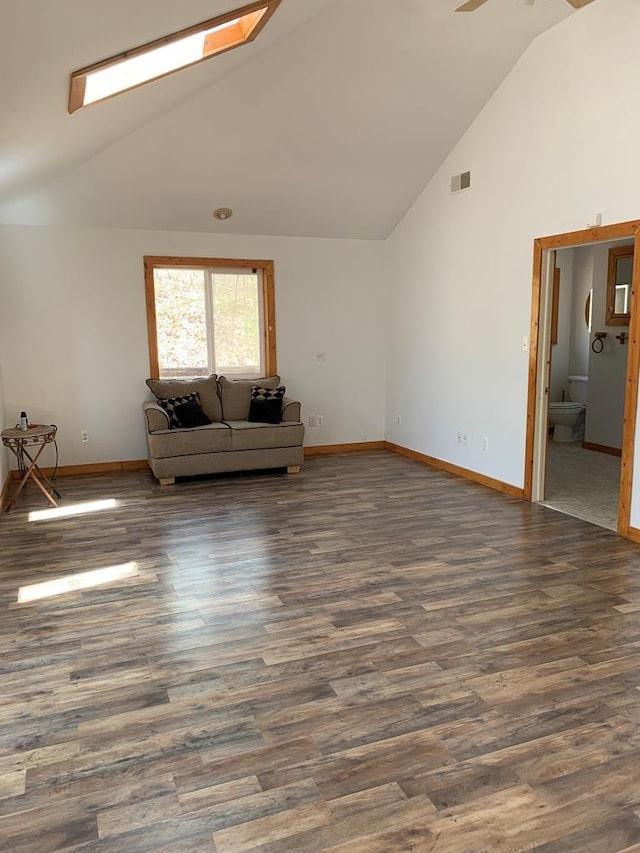 unfurnished living room with ceiling fan, dark wood-type flooring, high vaulted ceiling, and a skylight