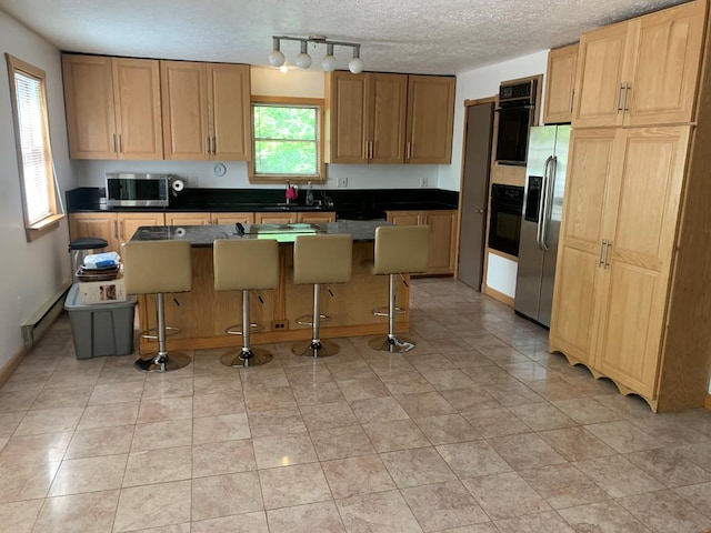 kitchen featuring a textured ceiling, a center island, stainless steel appliances, and a breakfast bar area