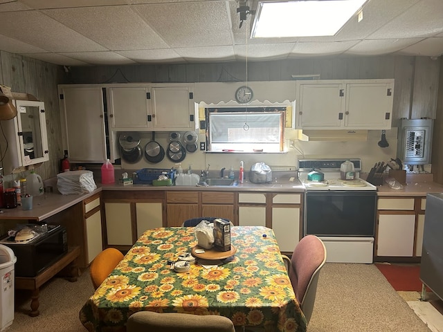 kitchen featuring white cabinets, wood walls, light colored carpet, and white electric range