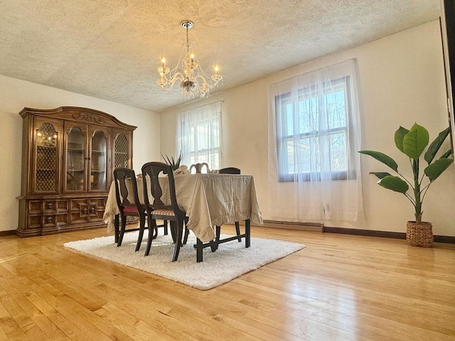 dining space featuring a textured ceiling, a notable chandelier, and light hardwood / wood-style floors