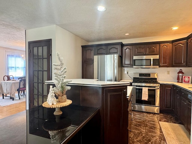 kitchen with dark brown cabinetry, decorative backsplash, and appliances with stainless steel finishes