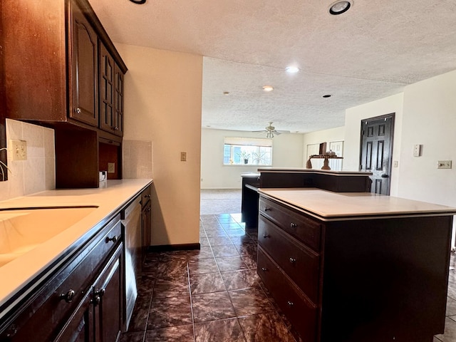 kitchen featuring sink, a center island, dark brown cabinets, a textured ceiling, and ceiling fan