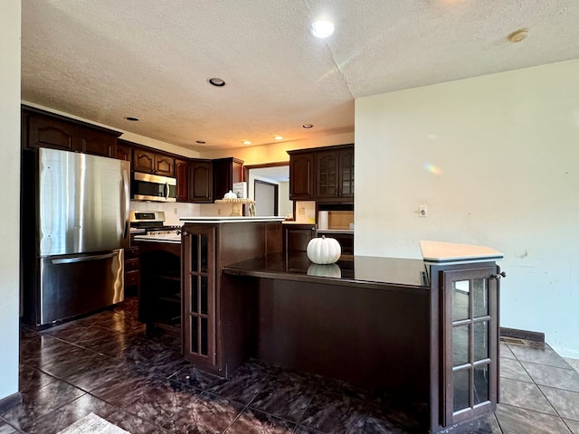 kitchen featuring dark brown cabinetry, stainless steel appliances, a center island, and a textured ceiling