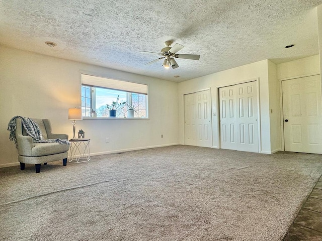 living area featuring ceiling fan, a textured ceiling, and dark carpet