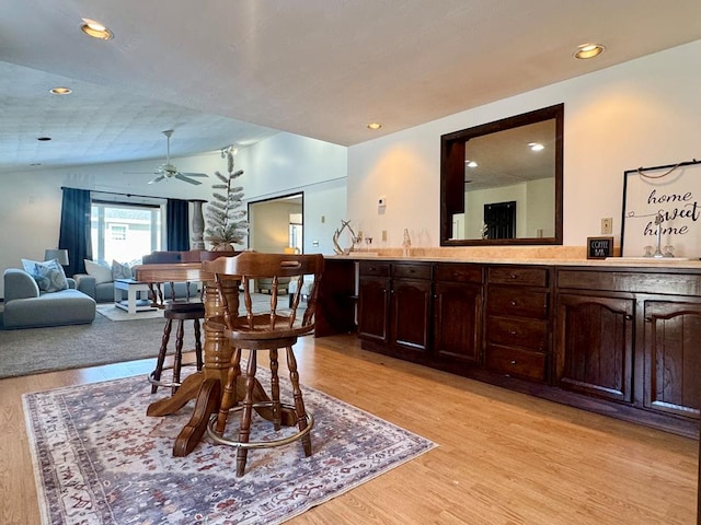 dining space featuring ceiling fan, lofted ceiling, sink, and light hardwood / wood-style flooring