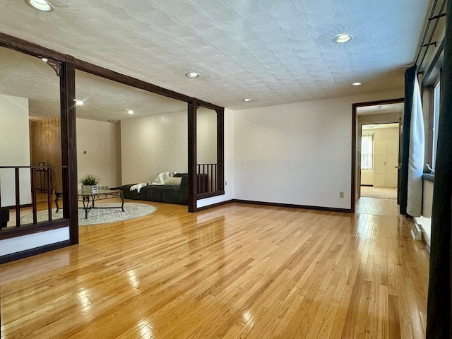 spare room with a textured ceiling and light wood-type flooring