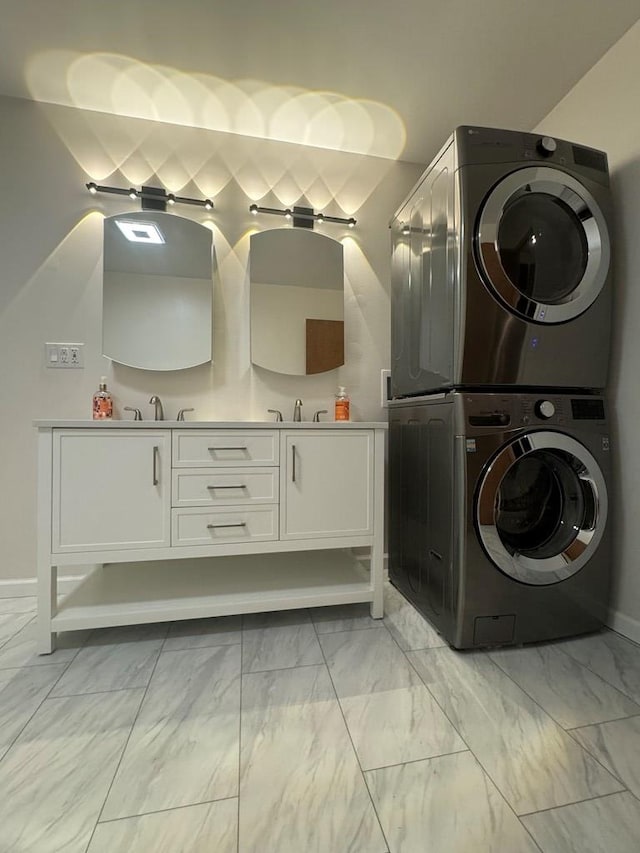 clothes washing area with cabinets, sink, and stacked washer and clothes dryer