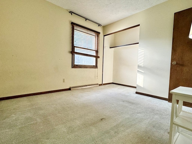 unfurnished bedroom with baseboard heating, light colored carpet, a closet, and a textured ceiling