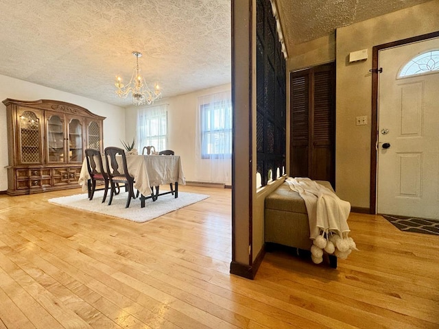 dining room featuring an inviting chandelier, light hardwood / wood-style floors, and a textured ceiling