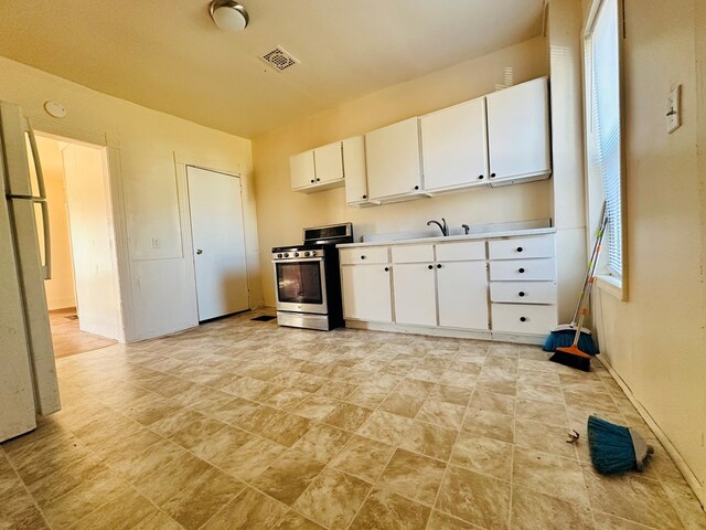 kitchen with white cabinets, white refrigerator, sink, and stainless steel stove