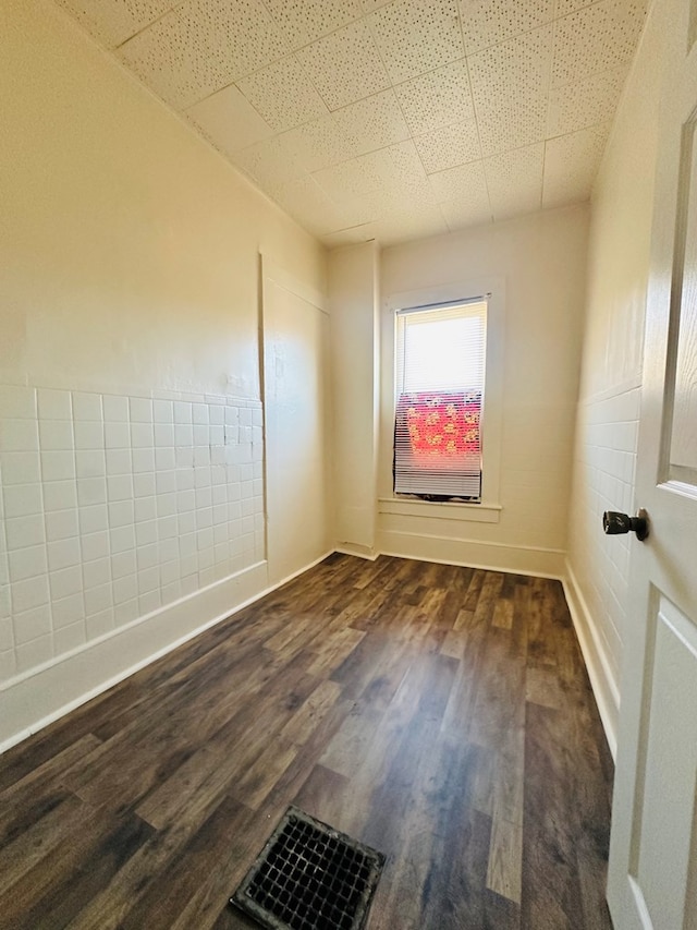 empty room featuring a drop ceiling and dark hardwood / wood-style floors