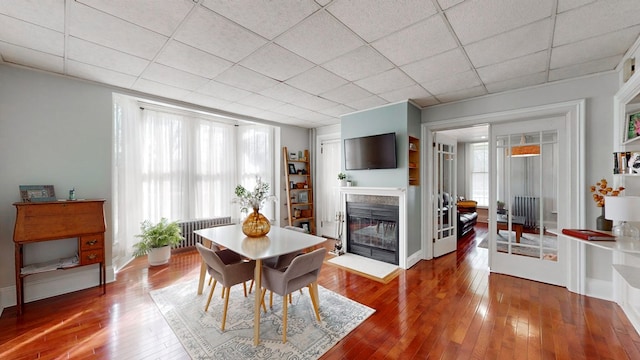 dining space featuring hardwood / wood-style floors, radiator heating unit, and a healthy amount of sunlight