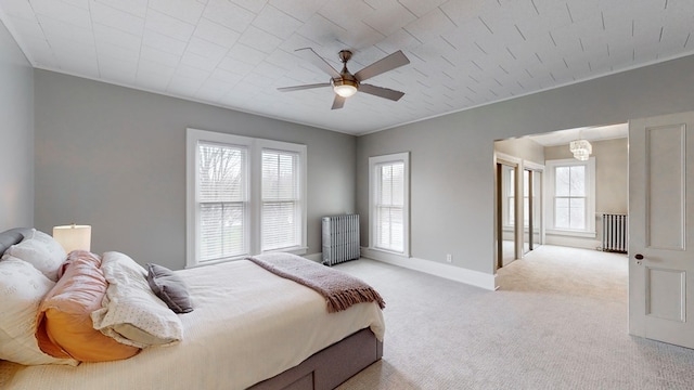 carpeted bedroom featuring radiator heating unit, ceiling fan with notable chandelier, and multiple windows