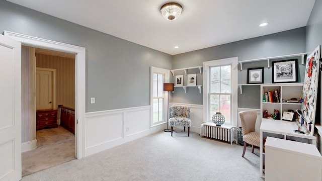 sitting room featuring radiator, light carpet, and a wealth of natural light