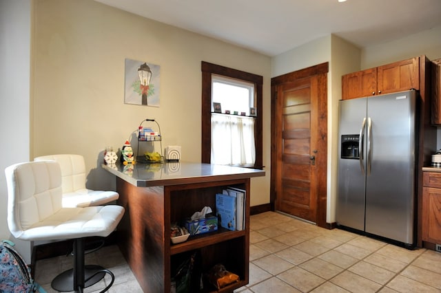 kitchen featuring kitchen peninsula, light tile patterned flooring, and stainless steel refrigerator with ice dispenser