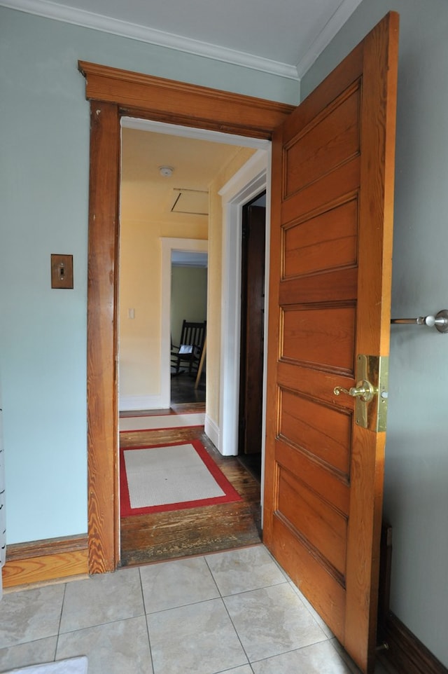 hall featuring light tile patterned floors and crown molding