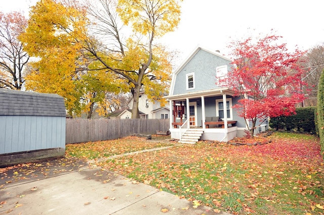 view of front of property featuring a porch and a shed