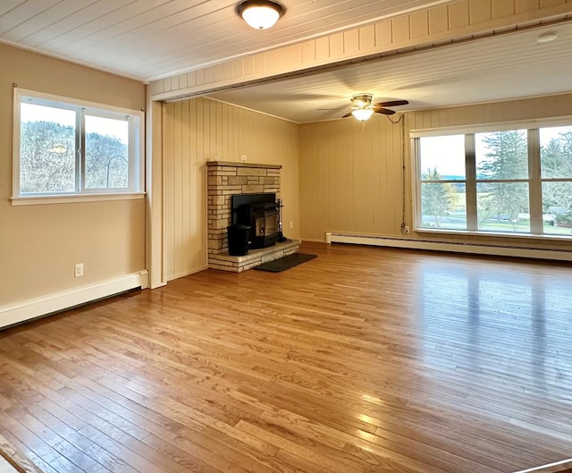 unfurnished living room featuring hardwood / wood-style flooring, plenty of natural light, and baseboard heating