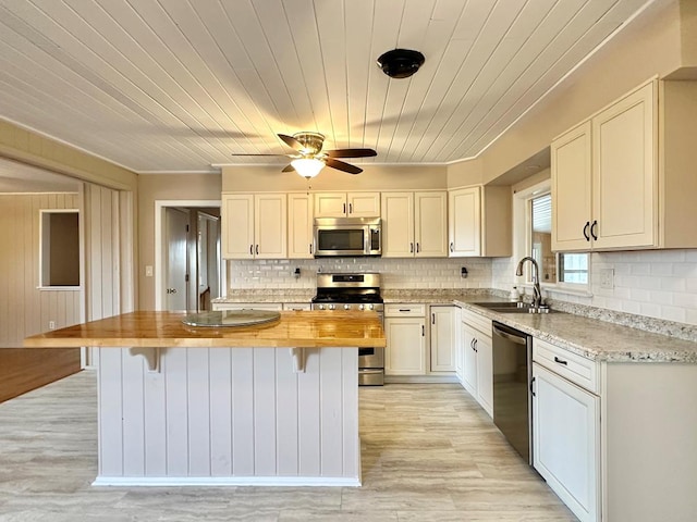 kitchen with sink, butcher block countertops, white cabinetry, a kitchen island, and stainless steel appliances