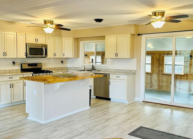 kitchen featuring stainless steel appliances, a kitchen island, sink, and white cabinets