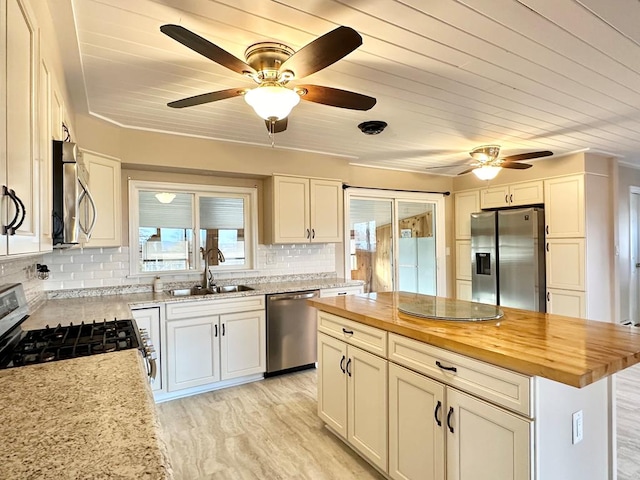 kitchen with butcher block countertops, sink, white cabinets, a center island, and stainless steel appliances