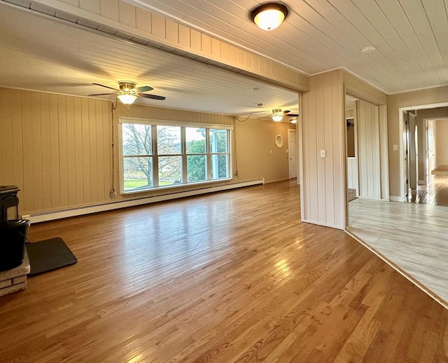 unfurnished living room with light hardwood / wood-style flooring, wooden ceiling, baseboard heating, and a wood stove