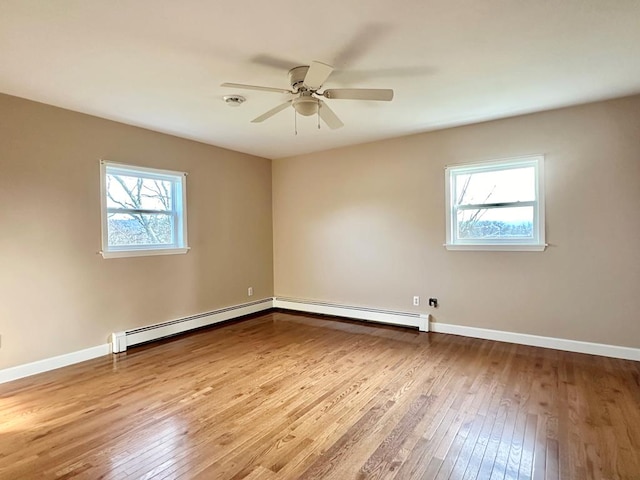 spare room with hardwood / wood-style flooring, a baseboard radiator, and a wealth of natural light