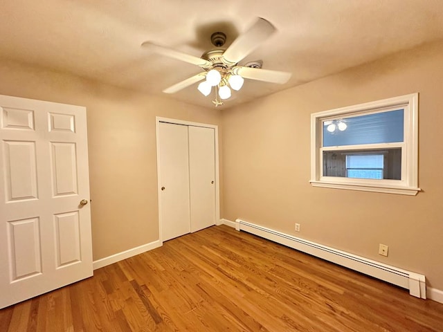 unfurnished bedroom with ceiling fan, a baseboard radiator, a closet, and light wood-type flooring