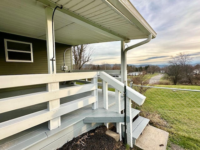 deck at dusk featuring a lawn