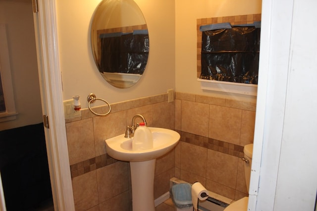 bathroom featuring toilet and tile walls