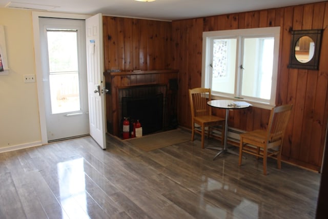 sitting room featuring hardwood / wood-style flooring, wooden walls, and a large fireplace