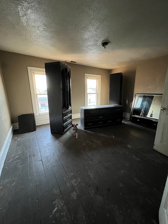 unfurnished living room with plenty of natural light, a textured ceiling, and dark hardwood / wood-style flooring