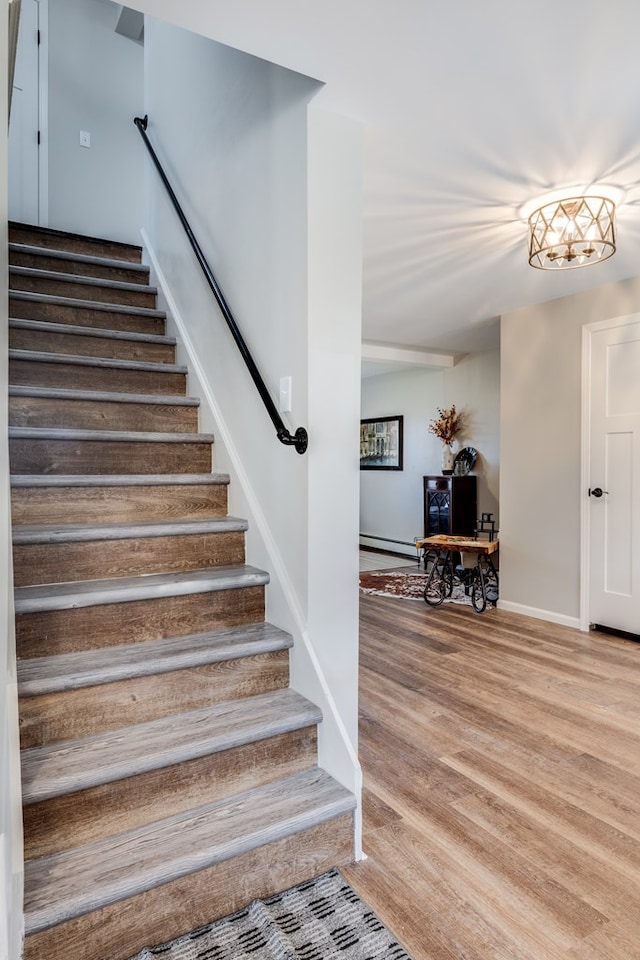 staircase with hardwood / wood-style floors and a baseboard heating unit