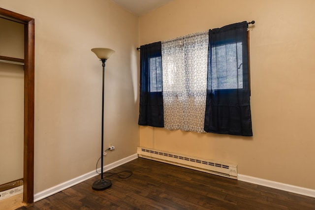 unfurnished bedroom featuring dark wood-type flooring and a baseboard radiator