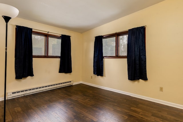 spare room with dark hardwood / wood-style flooring, a healthy amount of sunlight, and a baseboard heating unit