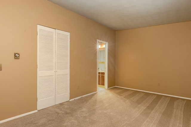 unfurnished bedroom featuring light carpet and a closet