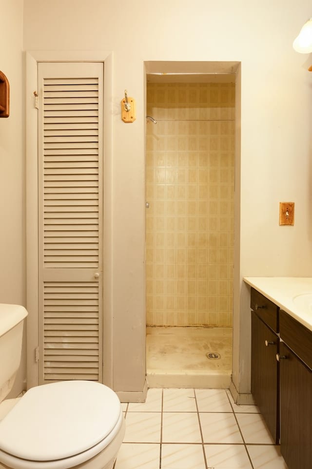 bathroom with tile patterned floors, toilet, a tile shower, and vanity